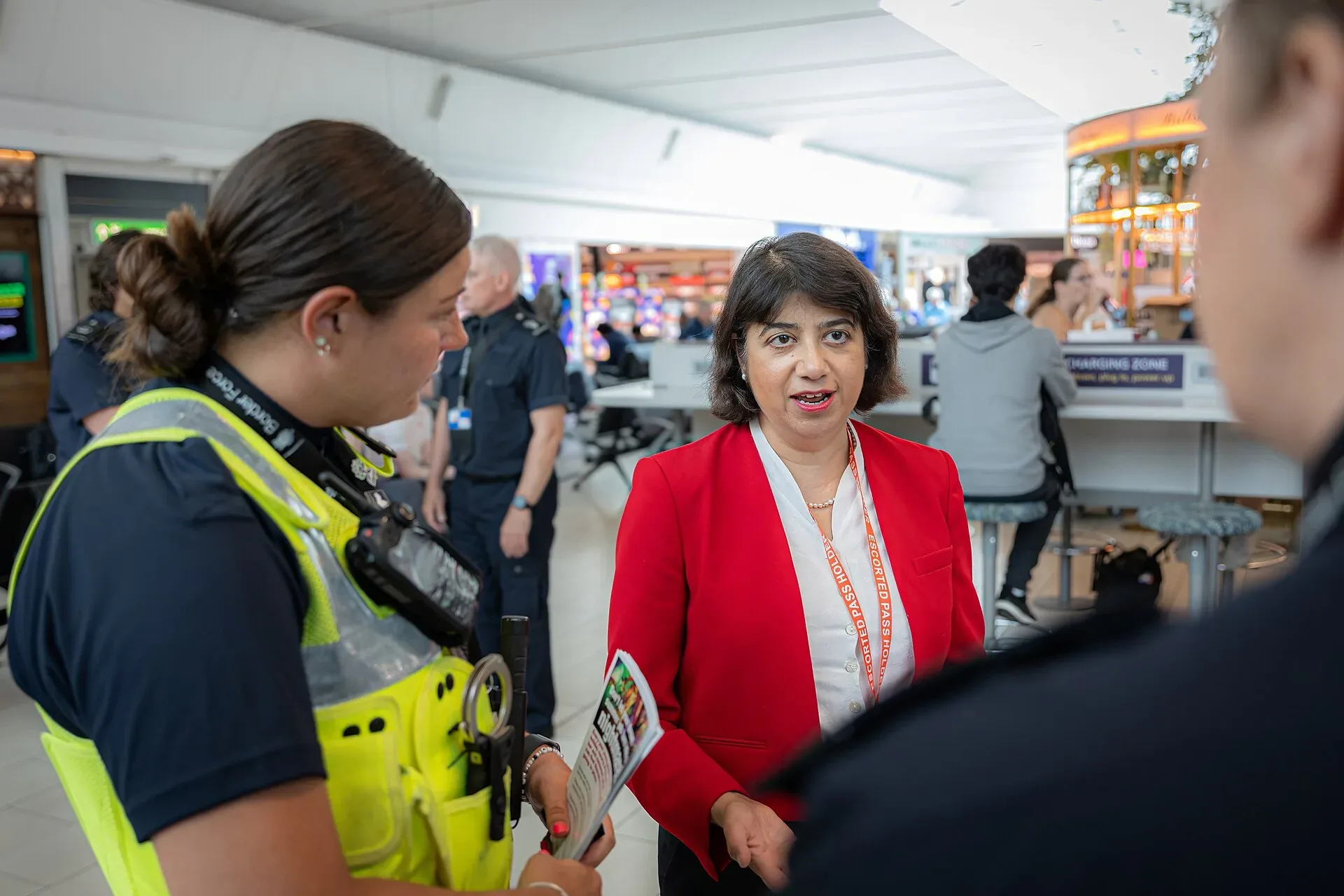 Border Force officers talking with a government minister in an airport terminal
