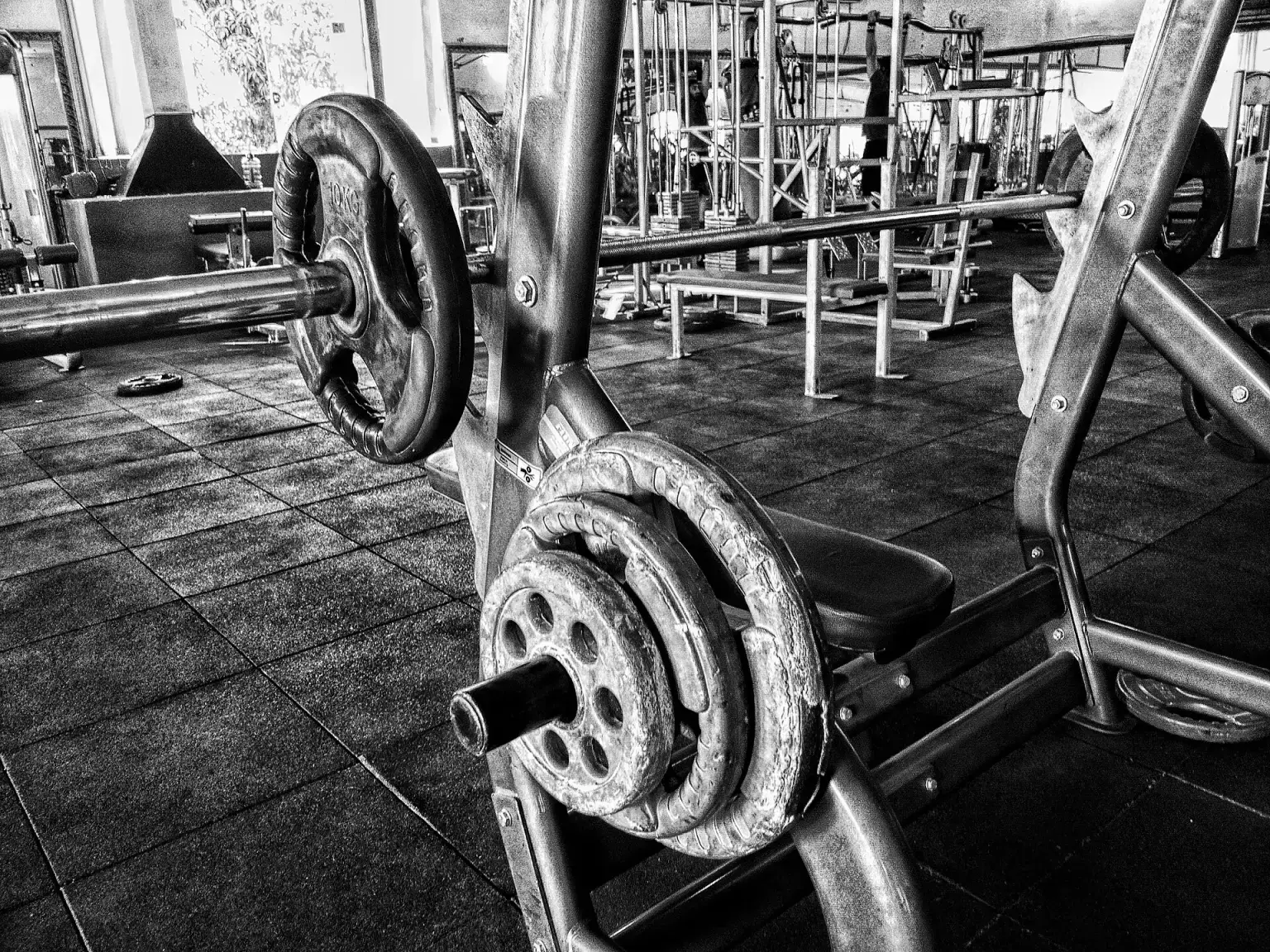 A barbell and weight plates on a bench press in a gym