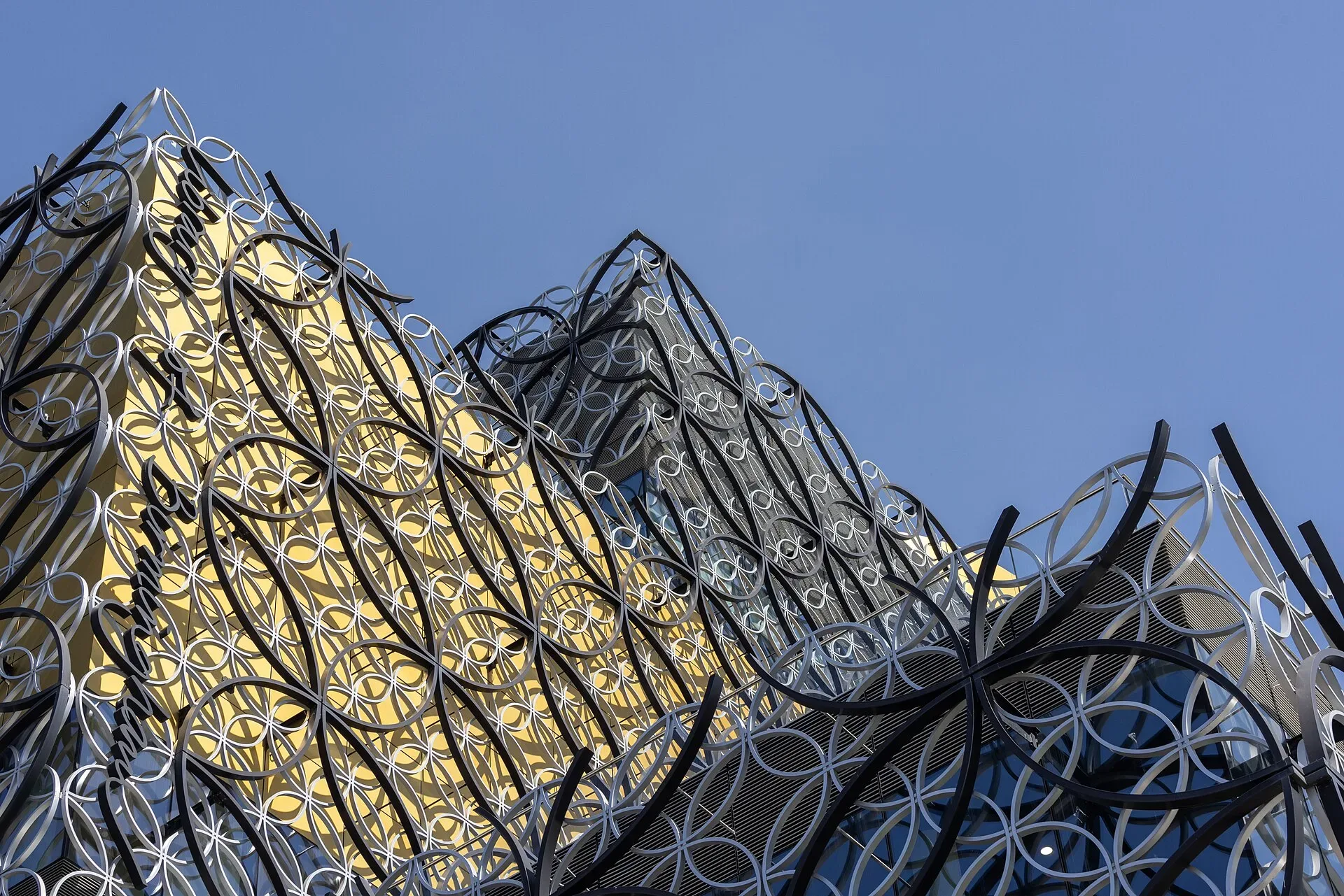 The patterned metal facade of the Library of Birmingham against a blue sky