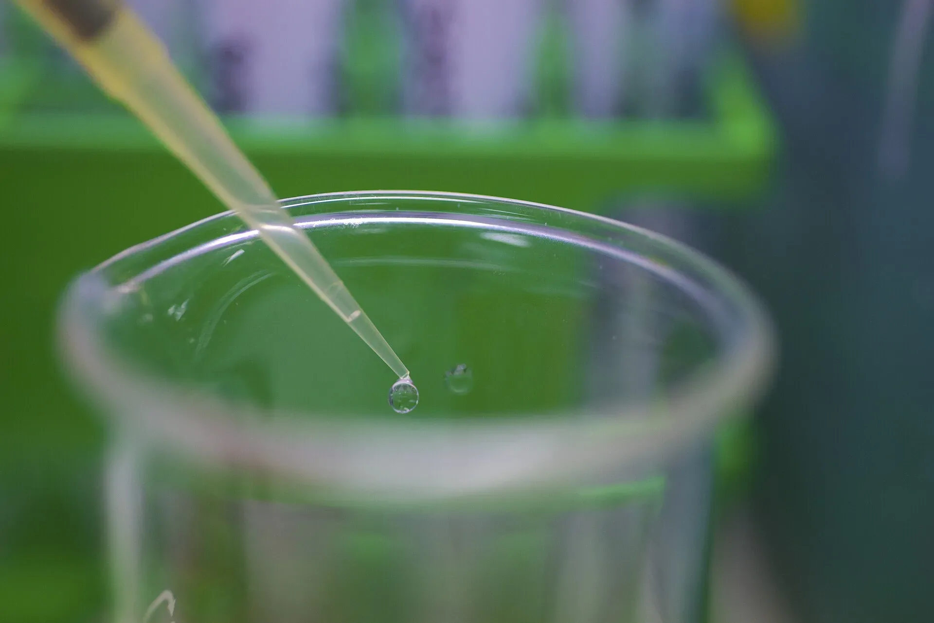 A drop of liquid falling from a pipette into a laboratory beaker