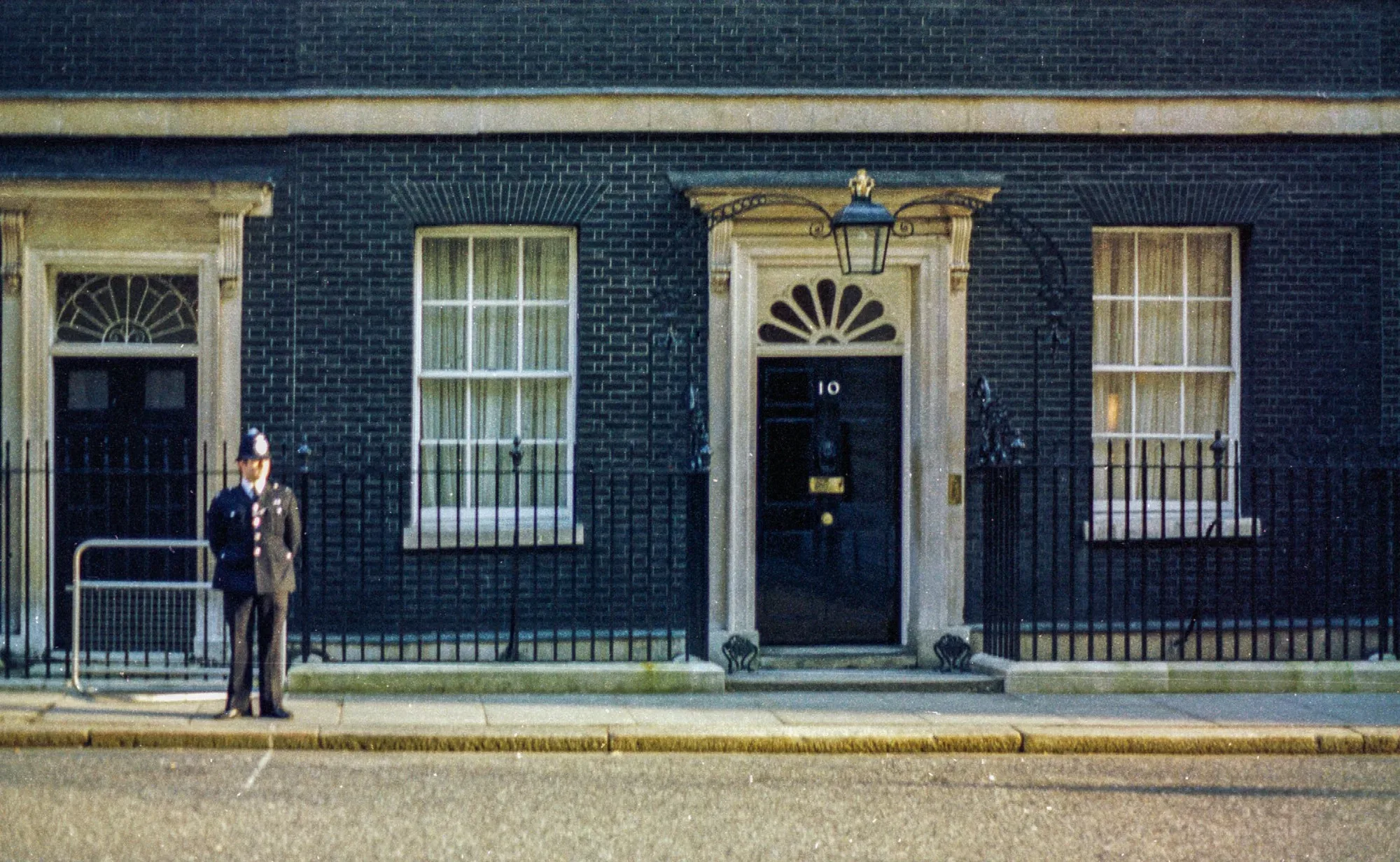 The black front door of 10 Downing Street with a police officer on duty
