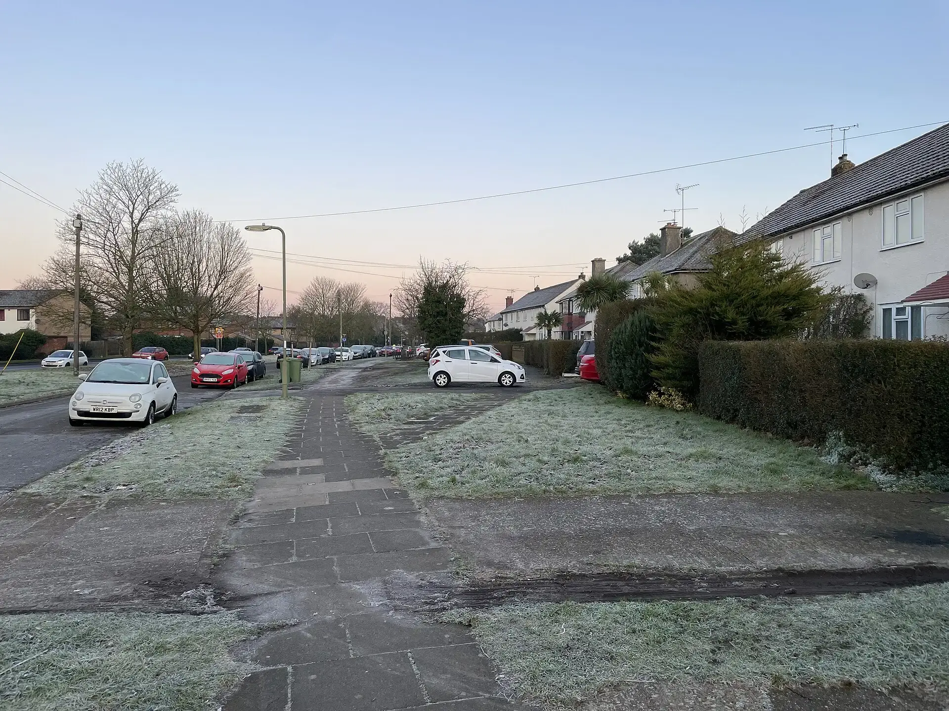 Frost covering the grass verges of a suburban street early in the morning