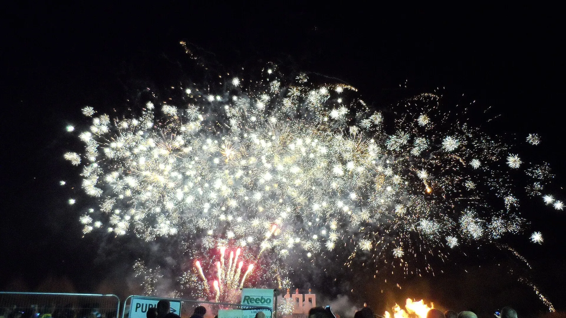 Fireworks bursting in the night sky above a crowd at a Bonfire Night display