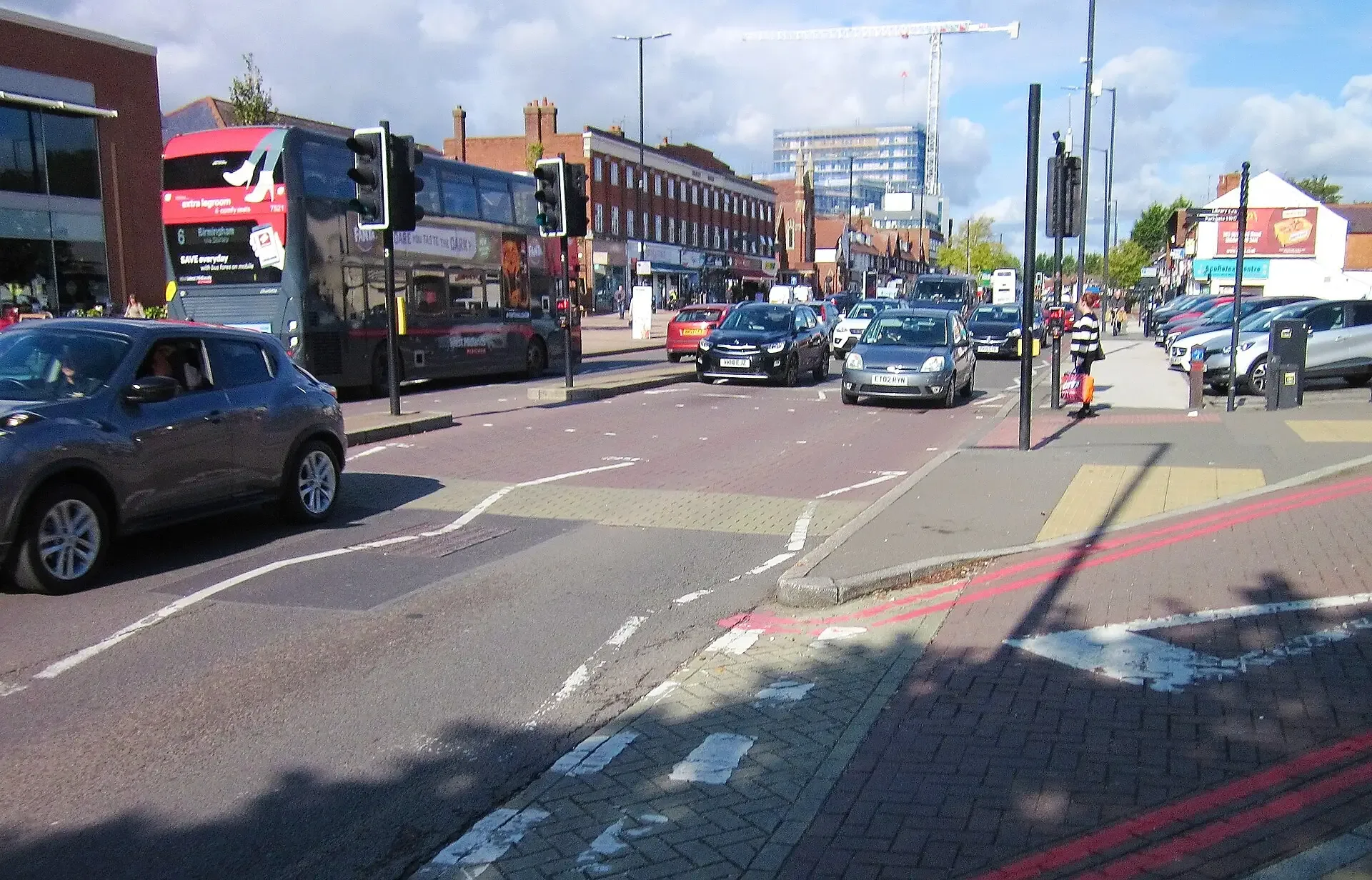 Traffic and shops along Stratford Road in Shirley on a sunny day