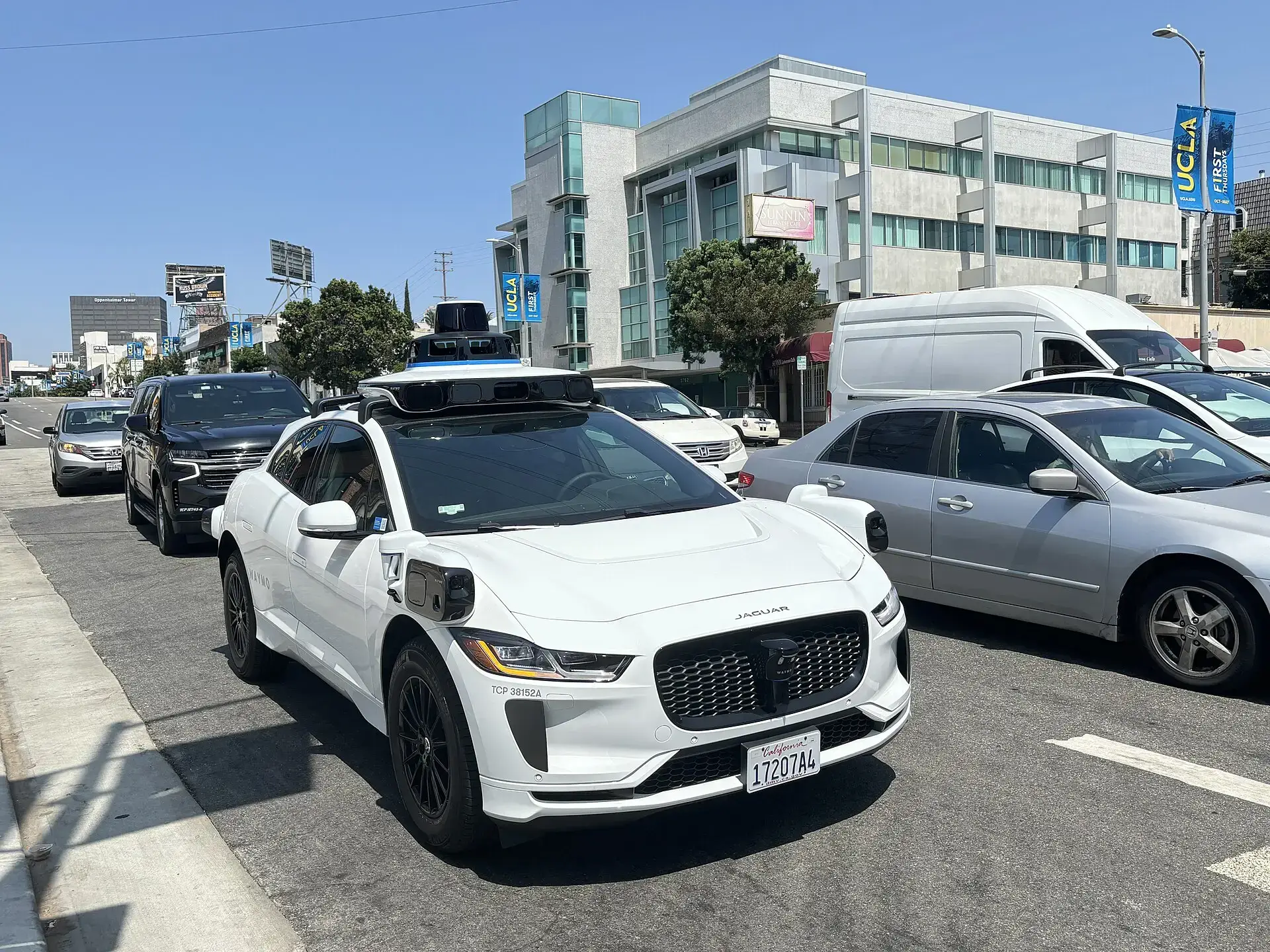 A white Jaguar I-Pace fitted with Waymo self-driving sensors on a city street