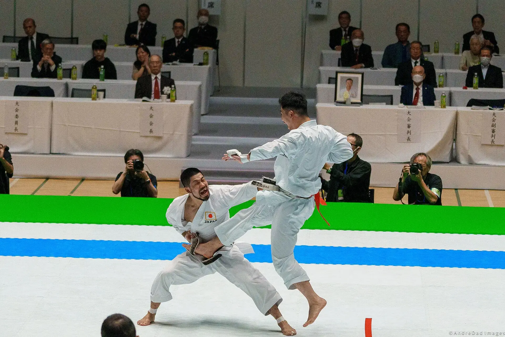 Two karate fighters competing in a kumite final in front of judges